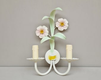 Wandlamp vervaardigd uit metaal en voorzien van bloemendecor.