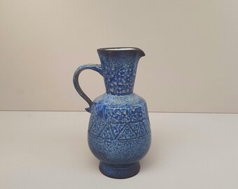Könnte beinhalten: Eine blaue Keramikkanne mit strukturierter Oberfläche und geometrischem Muster. Die Kanne hat eine breite Öffnung und einen Henkel.