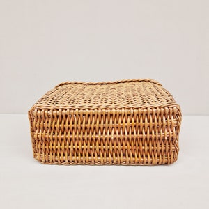 May include: A woven wicker basket with a rectangular shape. The basket is made of natural brown wicker and has a smooth, even weave.