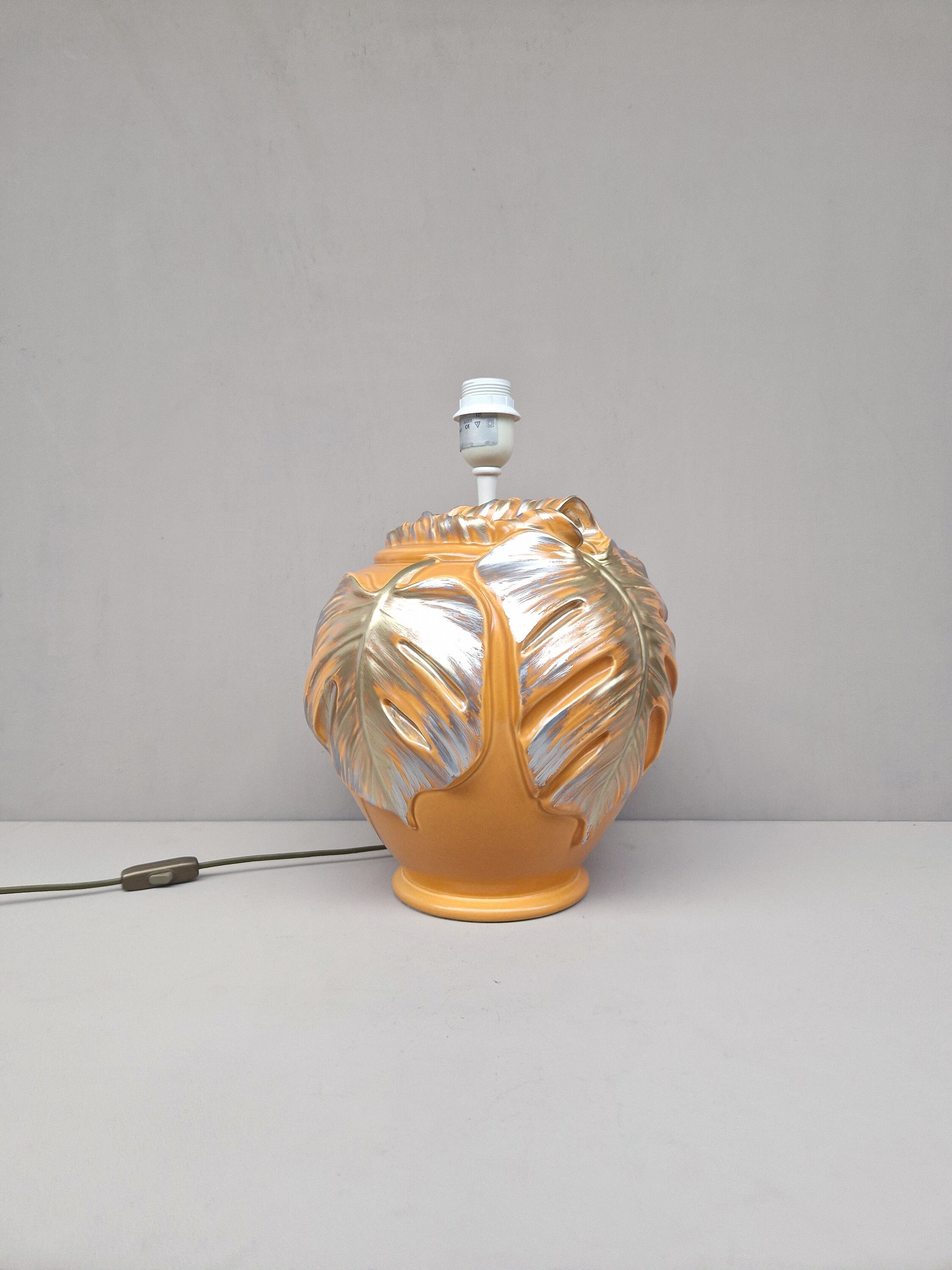 Vintage grote lampenvoet in de kleur zacht oranje voorzien van in relief gedecoreerde bladeren in goud- en zilverkleur, jaren '80