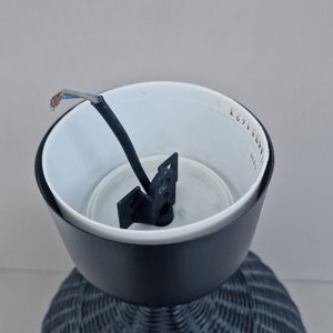 May include: Black wicker lampshade with a white interior and a black wire hanging from the top. The lampshade has a white sticker with the text "2671 3EW" on the side.