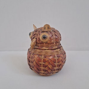 May include: A woven wicker owl-shaped trinket box with black eyes. The box is brown and has a woven pattern.