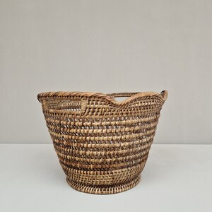 May include: A woven wicker basket with a rounded, scalloped top and a natural brown color.