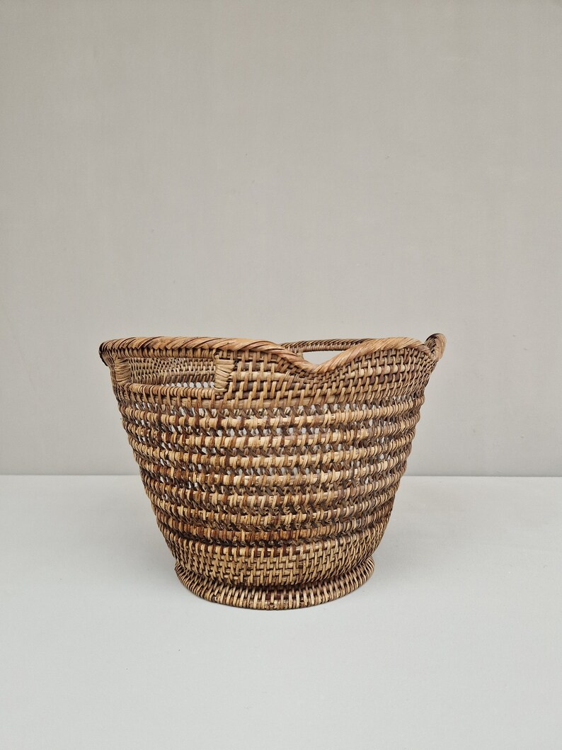 May include: A woven wicker basket with a rounded, scalloped top and a natural brown color.