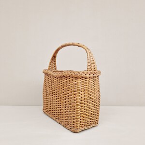 May include: A woven wicker tote bag with a natural brown color and a single handle.