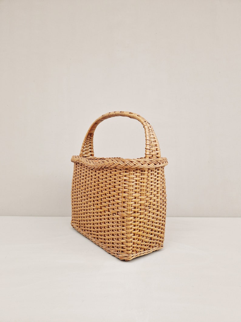 May include: A woven wicker tote bag with a natural brown color and a single handle.