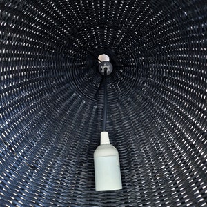 May include: A black wicker lampshade with a white electrical cord and a white light bulb socket.