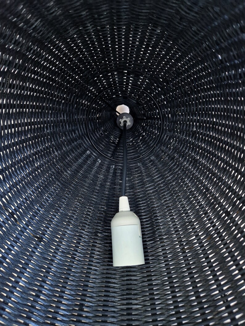 May include: A black wicker lampshade with a white electrical cord and a white light bulb socket.