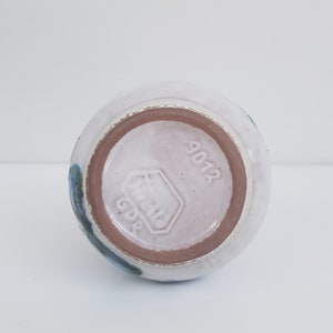 K&ouml;nnte beinhalten: Die Unterseite einer wei&szlig;en Keramikvase mit blauem und braunem &Uuml;berzug. Die Vase ist mit "GDR" und "9012" gestempelt.