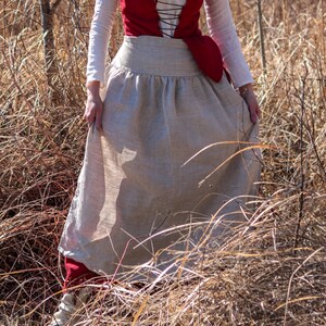 Puede incluir: Una mujer con un top rojo y blanco y una falda larga de lino fluida. La falda es de color beige claro y tiene la cintura fruncida.