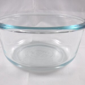 May include: A clear glass mixing bowl with a rounded shape and a slightly flared rim. The rim has a subtle blue tint. The bowl is designed for food preparation and is suitable for various kitchen tasks.