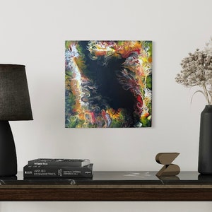 Pode incluir: Pintura abstrata com cores que giram em amarelo, laranja, vermelho, verde e branco em torno de um centro preto.