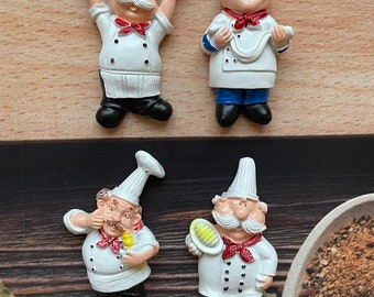 May include: Four white ceramic chef figurines with red accents. One chef holds a sign that says "WELCOME". Another chef holds a white towel. The other two chefs hold a spatula and a whisk.