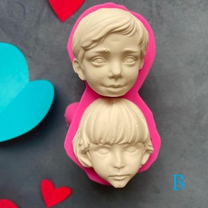 Può includere: Stampo in silicone rosa con due impressioni di volti di bambini. Lo stampo è per realizzare topper per torte o altri articoli decorativi.