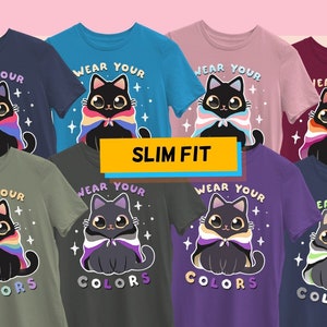 May include: Seven t-shirts in different colors with a black cat wearing a rainbow pride flag as a cape. The text on the shirts reads "Wear Your Colors".