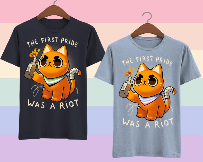 Puede incluir: Dos camisetas con un gr&aacute;fico de un gato naranja sosteniendo un c&oacute;ctel Molotov. El texto en las camisetas dice "The first pride was a riot".