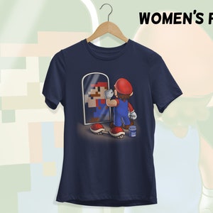 May include: A navy blue t-shirt with a graphic of a video game character looking in a mirror. The character is holding a paintbrush and is surrounded by a few video game items.