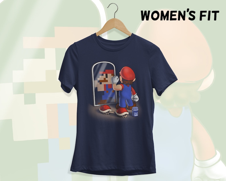 May include: A navy blue t-shirt with a graphic of a video game character looking in a mirror. The character is holding a paintbrush and is surrounded by a few video game items.
