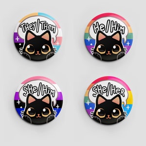 Puede incluir: Cuatro botones redondos con ilustraciones de gatos negros y banderas arco&iacute;ris del orgullo. Los botones muestran el texto "They/Them", "He/Him", "She/Him" y "She/Her".