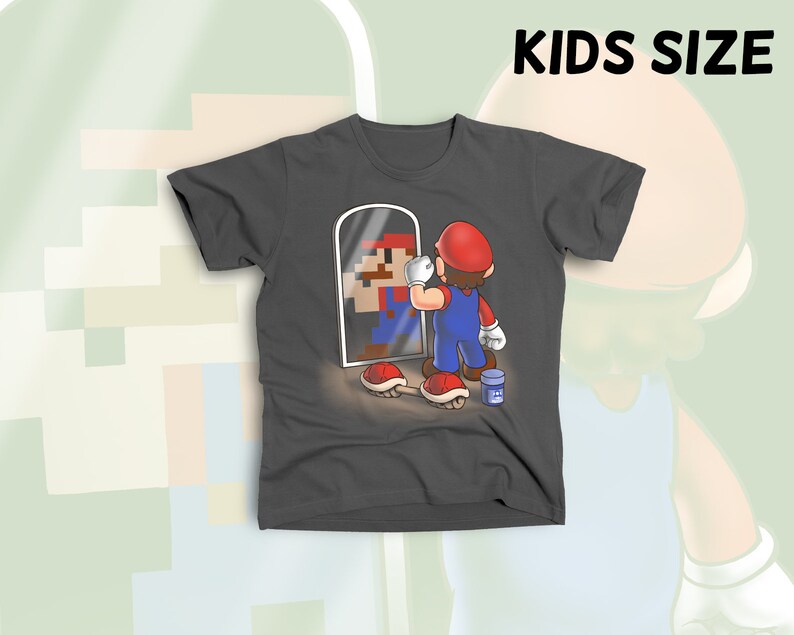 May include: A dark gray t-shirt with a cartoon image of a video game character looking in a mirror. The character is holding a paintbrush and a can of paint. The text "KIDS SIZE" is visible at the top of the image.