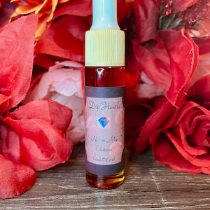 May include: A small glass bottle with a dropper top filled with a red liquid. The bottle has a black label with the text "Dip Hustle" and "Nut on My Cherries" in white. The label also includes the text "Cuticle Oil 10 ml".