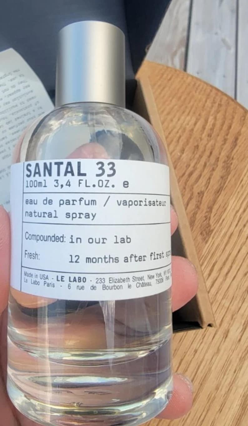 May include: Clear glass SANTAL 33 eau de parfum bottle with a silver cap. The label reads "100ml 3.4 FL.OZ. e" and "natural spray." The text also states "Compounded: in our lab" and "Fresh: 12 months after first."