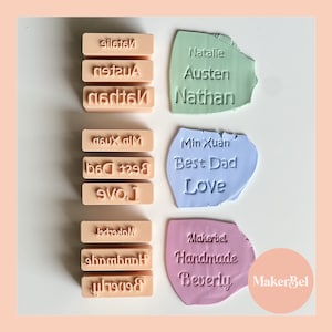 May include: A set of personalised stamps featuring names, phrases, and the MakerBel logo. The stamps are made from a light pink, light blue, and light green material. The stamps are arranged in three rows, with the top row containing the names Natalie, Austen, and Nathan. The middle row contains the phrases Min Xuan, Best Dad, and Love. The bottom row contains the phrases Makerbel, Handmade, and Beverly.