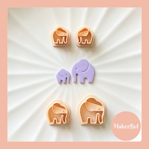 May include: A selection of elephant-shaped cookie cutters and cutouts. The cutters are light peach, and the cutouts are lavender. The elephant shapes vary in size, with a large and small cutout, and several cutters in the same shape.