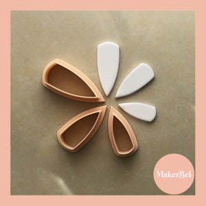 Peut inclure: Vue de dessus d'un arrangement floral de découpoirs à biscuits en forme de pétales beiges et de pétales en fondant blancs. Les découpoirs sont en plastique brun clair et sont disposés en cercle autour des pièces de fondant blanc.