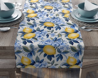 May include: A white table runner with a lemon and blue floral pattern. The runner is on a wooden table with place settings.