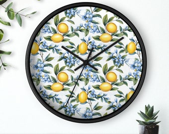 May include: A black wall clock with a white background and a repeating pattern of yellow lemons and blue flowers. The clock hands are black.