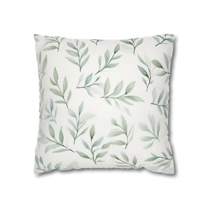 May include: A white throw pillow with a green watercolor leaf pattern.