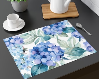 May include: A white placemat with a watercolor design of blue and purple hydrangeas and green leaves.