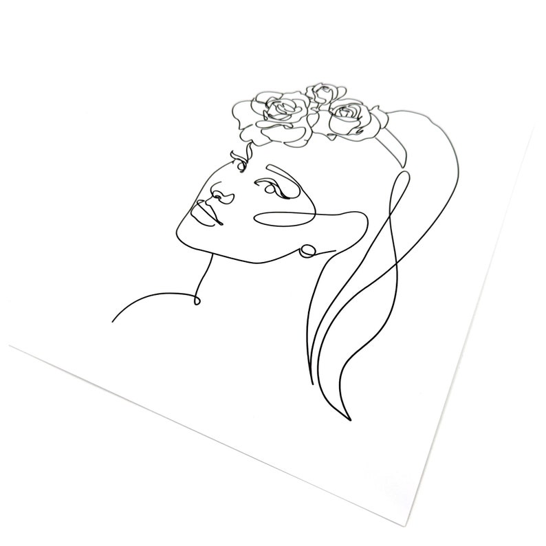 Puede incluir: Un dibujo lineal minimalista del rostro de una mujer, mirando hacia arriba, adornado con una corona floral. La obra de arte est&aacute; representada en una sola l&iacute;nea negra continua sobre un fondo blanco, enfatizando los rasgos delicados y el cabello suelto.