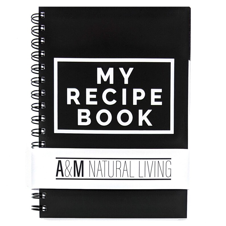 May include: Black spiral bound notebook with white text that reads "MY RECIPE BOOK" and a white label that reads "A&M NATURAL LIVING".