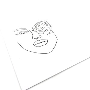 Puede incluir: Una impresi&oacute;n art&iacute;stica minimalista que representa el rostro de una mujer con una rosa. La obra de arte est&aacute; realizada con una sola l&iacute;nea negra sobre un fondo blanco. La rosa est&aacute; colocada donde estar&iacute;a el ojo.