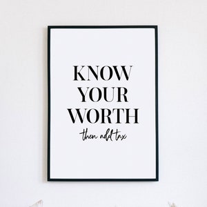 Puede incluir: Impresión enmarcada en blanco y negro con el texto "KNOW YOUR WORTH then add tax". La impresión está colgada en una pared blanca sobre un sofá blanco con tres almohadas.