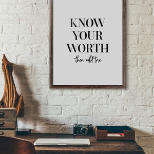 May include: A framed motivational poster with the text "KNOW YOUR WORTH then add tax" in black text on a white background.