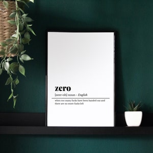May include: A framed print with the definition of "zero" in black text on a white background. The definition includes the pronunciation and a humorous explanation. The frame is black, and the print is displayed against a dark green wall.