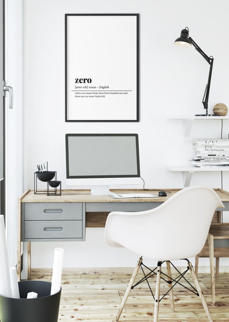May include: A modern office setup featuring a desk with a computer, a white chair, and a framed print. The print has the word "zero" with a definition. A black desk lamp and decorative items complete the workspace.