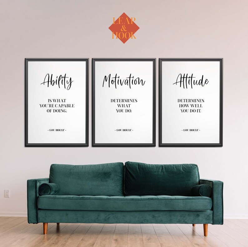 May include: Three black framed motivational posters with white backgrounds and black text. The posters are hung on a white wall above a teal green sofa. The text on the posters reads: "Ability is what you're capable of doing", "Motivation determines what you do", and "Attitude determines how well you do it". All three posters are attributed to Lou Holtz.