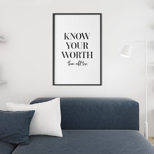 May include: A black and white framed print with the text "KNOW YOUR WORTH then add tax" hanging on a white wall in a living room setting.