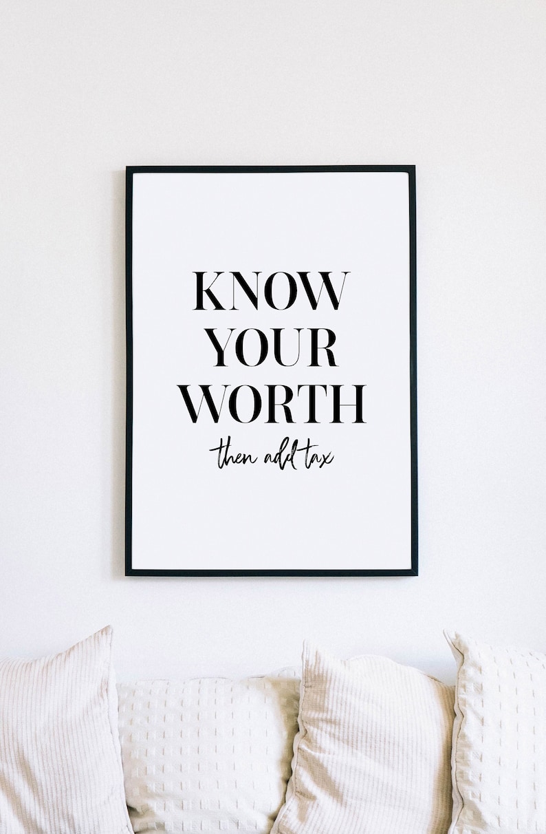 May include: Black and white framed print with the text "KNOW YOUR WORTH then add tax". The print is hanging on a white wall above a white sofa with three cushions.