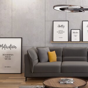 May include: A living room interior with a grey sofa and three framed motivational posters on the wall. The posters feature the words "Motivation", "Ability", and "Attitude" with inspirational quotes. The sofa has two yellow throw pillows.