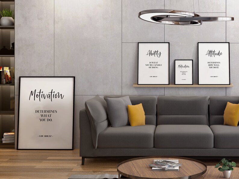 May include: A living room interior with a grey sofa and three framed motivational posters on the wall. The posters feature the words "Motivation", "Ability", and "Attitude" with inspirational quotes. The sofa has two yellow throw pillows.