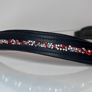 May include: Black leather horse bridle browband with a row of red and silver rhinestones. The browband is curved and padded for comfort. The rhinestones are arranged in a linear pattern.