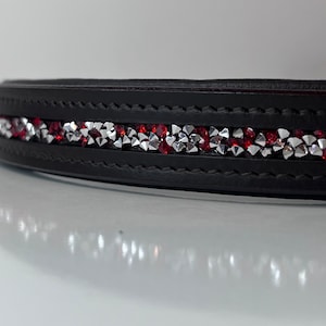 May include: Black leather collar with a row of alternating red and silver rhinestones. The collar is stitched and has a curved shape, suitable for a pet.