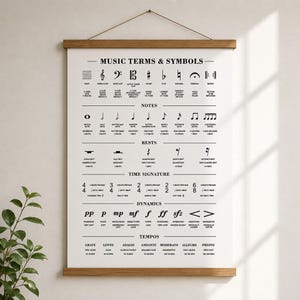 A black poster with white text and musical symbols, titled "MUSIC TERMS & SYMBOLS," hangs from a wooden dowel on a light wall.