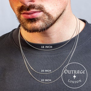 Puede incluir: Tres collares de cadena plateada de diferentes longitudes, 16 pulgadas, 20 pulgadas y 22 pulgadas, se muestran en el cuello de una persona. Las cadenas están superpuestas. La imagen también incluye el texto "OUTRAGE LONDON" con un símbolo de rayo.
