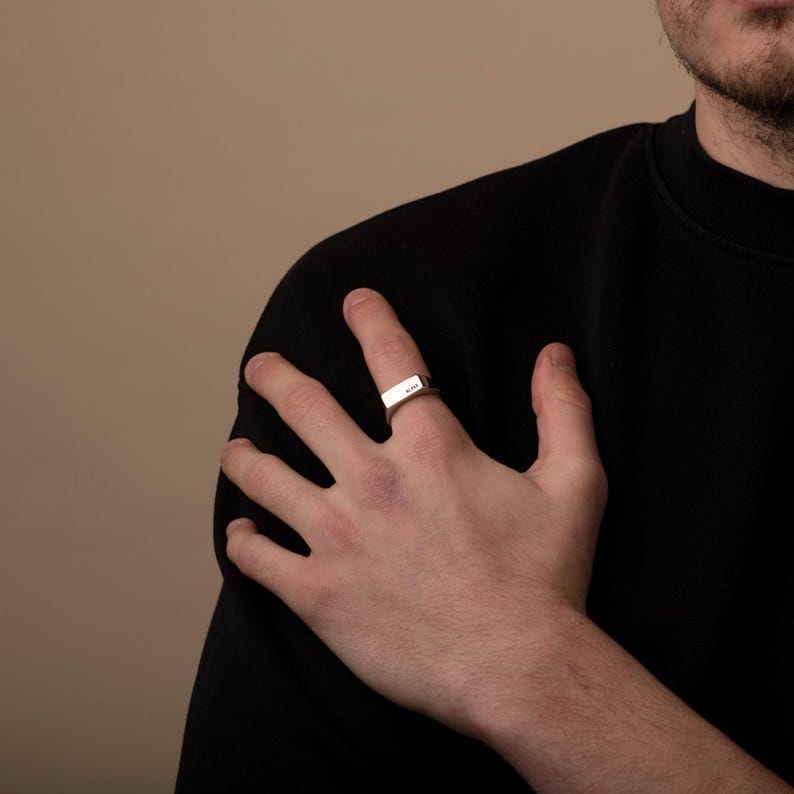 a man wearing a black shirt and a gold ring
